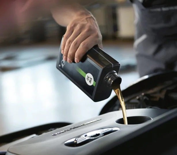 A certified MINI technician changing oil.