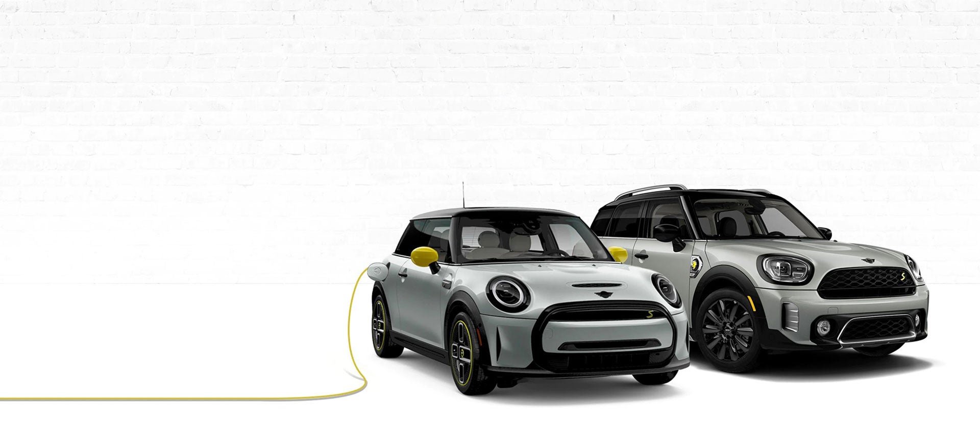 Two MINI Electric vehicles with one on left being charged.