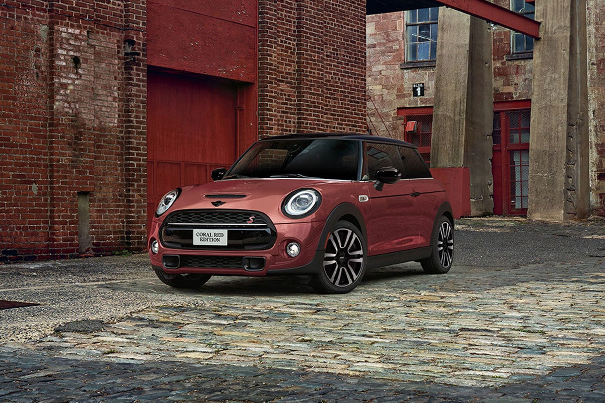 The MINI COOPER HARDTOP CORAL RED EDITION parked on a cobblestone road.