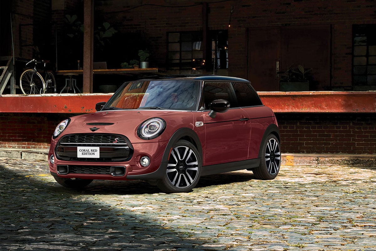 The MINI COOPER HARDTOP CORAL RED EDITION parked on a cobblestone road.