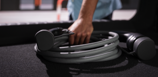 A person grabs an electric vehicle charger from their trunk.