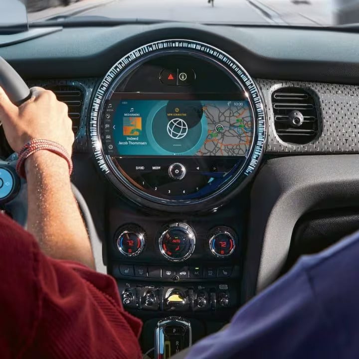View of the front row of a MINI vehicle pictured from the back row of a MINI vehicle, zooming in on the touchscreen media display and dashboard.