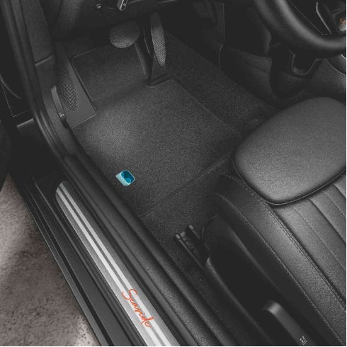 Closeup view of the interior of a MINI Cooper S Convertible Seaside Edition, particularly the door sills with the SEASIDE 30 insignia in brushed alloy and the floor mat piercing.
